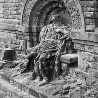 Sculpture of seated figure in stone niche.