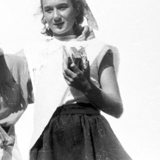 Three women in vintage attire holding small microphones on stage.