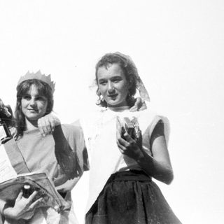 Three women in vintage attire holding small microphones on stage.
