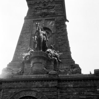 Monumental equestrian statue atop historic tower.