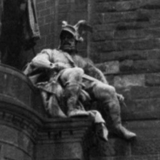 Monumental equestrian statue atop historic tower.