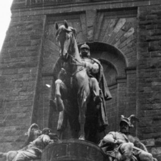 Monumental equestrian statue atop historic tower.