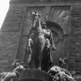 Monumental equestrian statue atop stone tower.