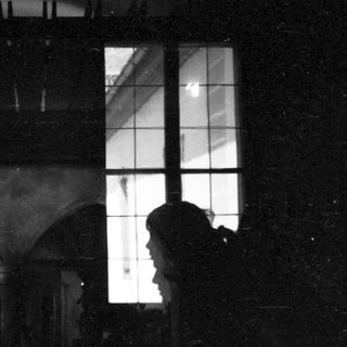 Silhouette of person looking through arched window.