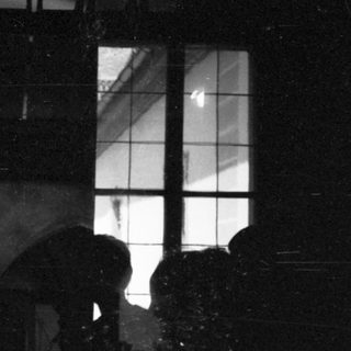 Silhouette of person standing near window at night.