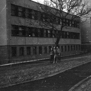 Two people walking alone at night near a building.