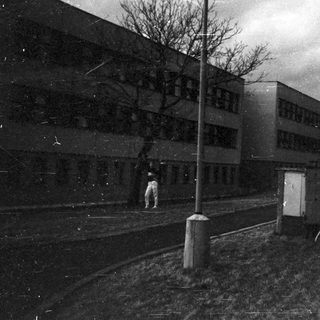 Isolated figure walking near abandoned buildings.