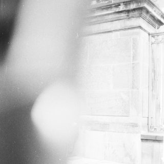 Blurred statue with classical architectural details.