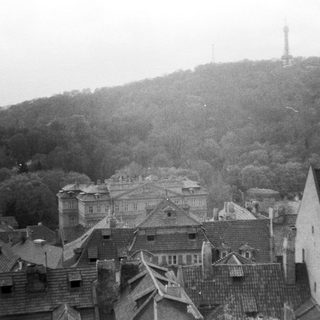 Historic town with hilltop tower and dense rooftops.