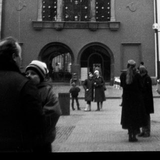 Historic European building with ornate facade and people walking outside.