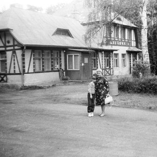Vintage photo of café "Kavarna" with two people outside.