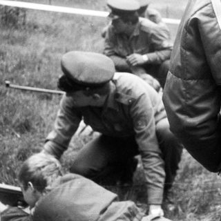 Soldiers assisting a fallen comrade outdoors.
