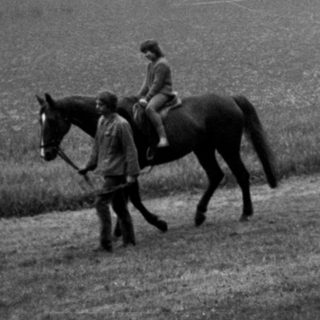 Two riders on horses in misty countryside.