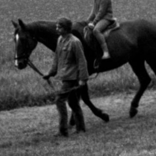Two riders on horses in misty countryside.