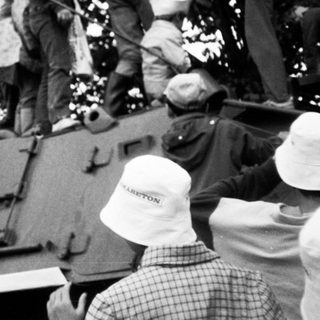 Soldiers inspecting or climbing on a vintage tank.
