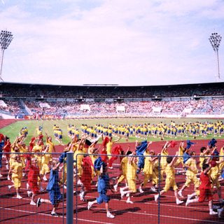 Massive stadium event with coordinated marching teams.
