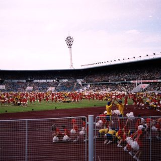 Massive stadium event with synchronized cheerleaders and crowd.