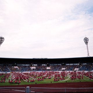Massive stadium crowd during large-scale synchronized performance.