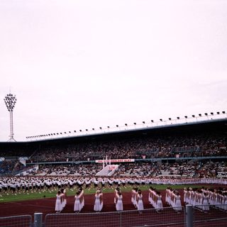 Massive stadium crowd with synchronized dance performance.