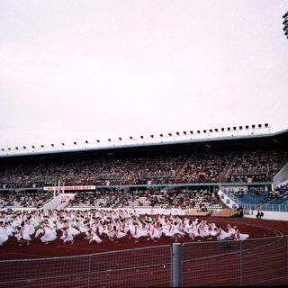 Massive stadium crowd during large-scale choreographed performance.