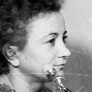 Nurse performing dental examination on patient using early dental equipment.