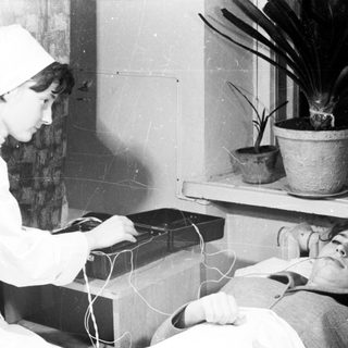 Medical professional performing electroconvulsive therapy on patient.