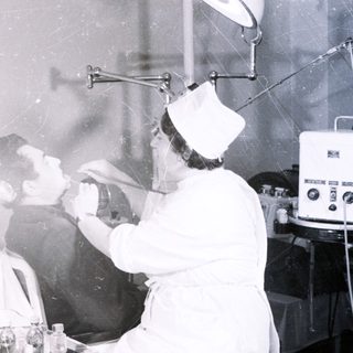Medical procedure using oxygen therapy in 1950s-style clinic.