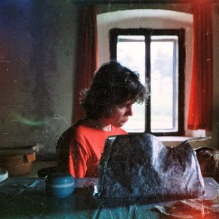 Woman preparing food in dimly lit kitchen.