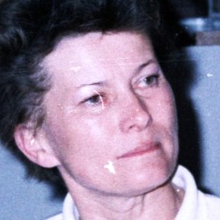 Woman in sportswear sitting indoors near glasses.