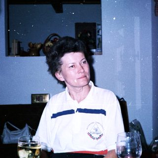 Woman in sportswear sitting indoors near glasses.