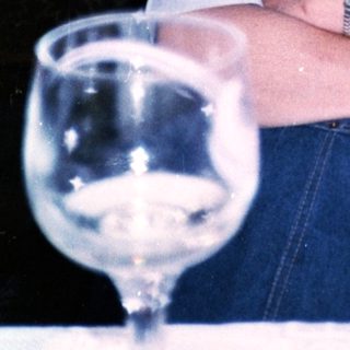 Woman smiling indoors with wine glass.
