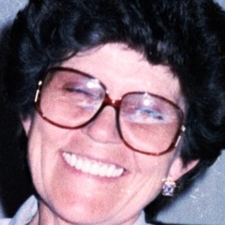 Woman smiling indoors with wine glass.