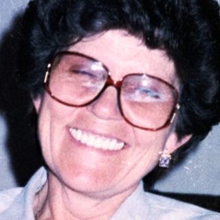 Woman smiling indoors with wine glass.