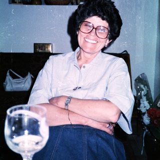Woman smiling indoors with wine glass.