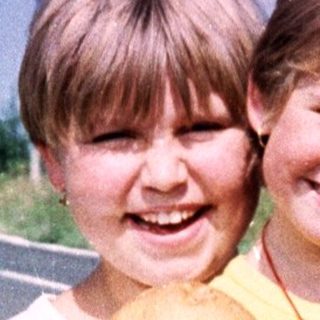 Two children holding mushrooms by the roadside.