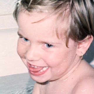 Child happily playing with bath toys in tub.