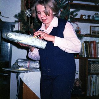 Young girl wrapping holiday gift near decorated Christmas tree.