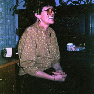 Woman smiling indoors near potted plants.