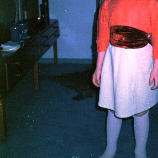 Young child wearing sunglasses, red sweater, and skirt.