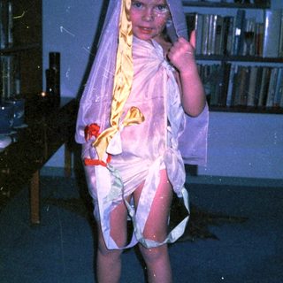 Child dressed as a bride in vintage wedding attire.