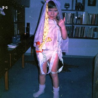 Child dressed as a bride in vintage wedding attire.
