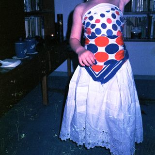 Young girl in polka-dot dress and headscarf indoors.