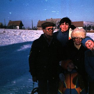 Four people posing together on snow-covered ground.