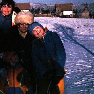 Four people posing together on snow-covered ground.