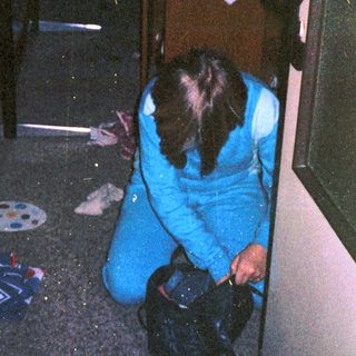Person cleaning floor with bucket in dimly lit room.