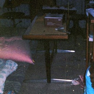 Person cleaning floor with bucket in dimly lit room.