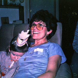 Woman and child smiling indoors with toy.