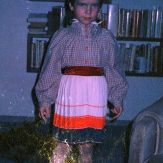 Child dressed as princess with flowing hair in dark room.