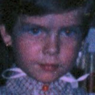 Child dressed as princess with flowing hair in dark room.