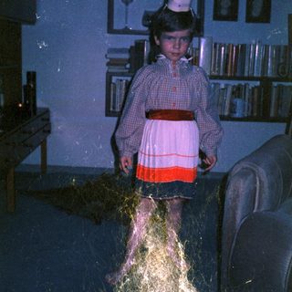Child dressed as princess with flowing hair in dark room.